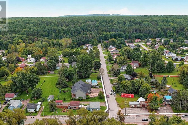 Aerial view of homes on a tree-lined street with forest background - 154 Robert Street W Penetanguishene