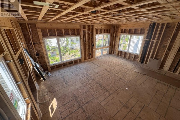 Interior room under construction with exposed wooden studs, framing, and plywood flooring. Several windows are visible. - 154 Terrastone Ridge, Dartmouth
