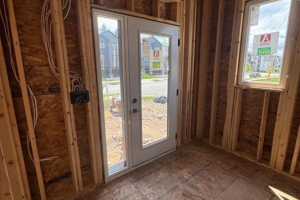 Interior room under construction with exposed wooden studs, a glass front door, and a window. - 154 Terrastone Ridge, Dartmouth