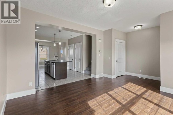 Open concept living area with dark hardwood floors, view into kitchen with island. - 1540 Mcalpine Street, Carstairs