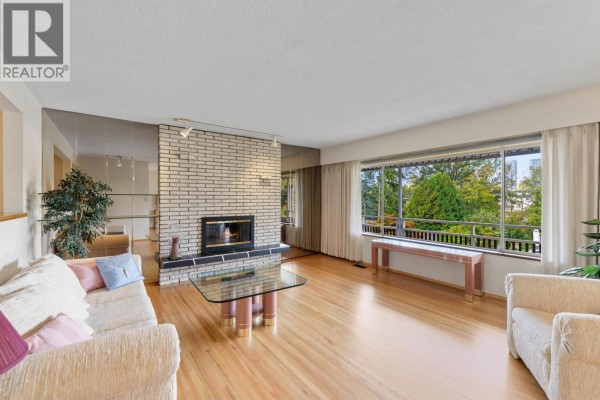 Living room showcasing a brick fireplace and large window with greenery view. - 1541 Howard Avenue, Burnaby