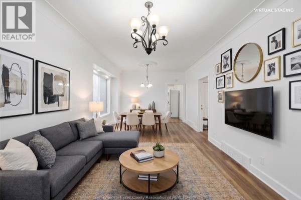 Living room with grey sectional sofa, round coffee table, wood floors, and gallery wall. - 1541 Lincoln Road, Windsor