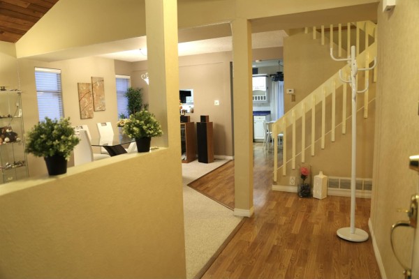 Interior view showing a staircase, hardwood floors, and an open living area with beige walls. - 15425 98th Avenue, Surrey