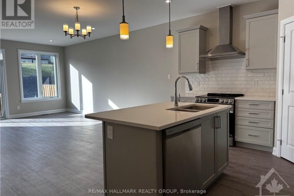 View of an open-concept kitchen and living area with a large island, stainless steel appliances, and a chandelier. - 1543 Flanders Road, Brockville