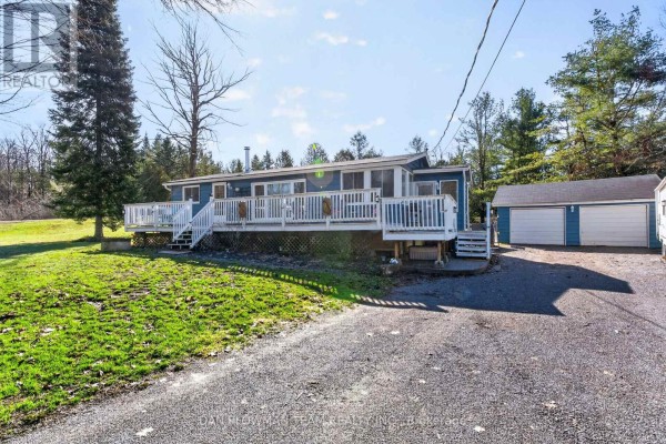 Rear exterior of a blue house with white deck, stairs, and a blue garage. - 1545 Westview Crescent, Selwyn