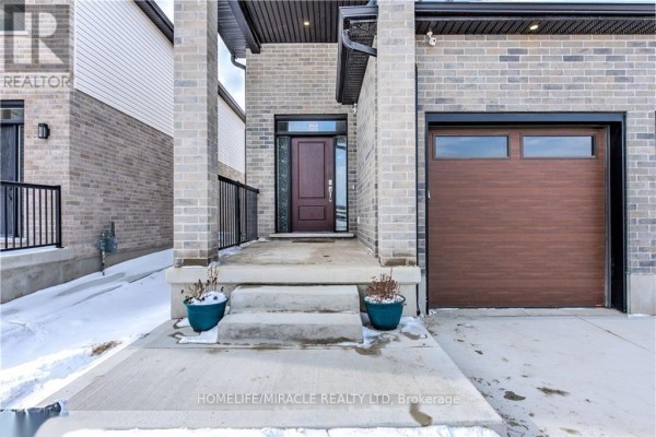 View of the house entrance with a dark wood door, concrete steps, and a single garage door. - 1546 Medway Park Drive, London North