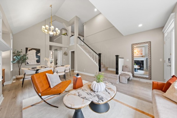 Living and dining area with vaulted ceiling, gas fireplace, orange chairs, and dining table. - 15460 36a Avenue, Surrey