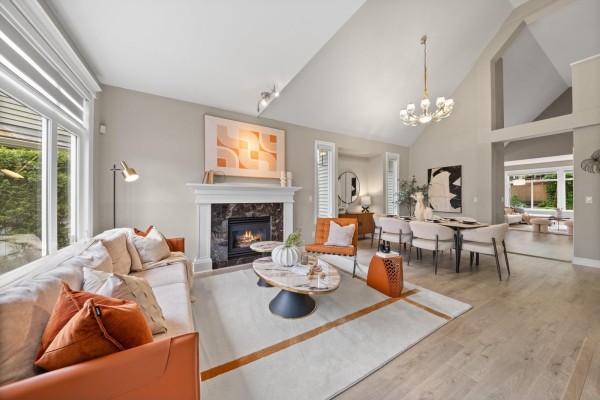 Living room with beige sectional sofa, gas fireplace, orange armchair, marble coffee table, and large window. - 15460 36a Avenue, Surrey