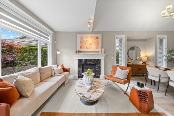 Living room with beige sectional sofa, marble coffee table, orange armchair, and a view of a backyard. - 15460 36a Avenue, Surrey