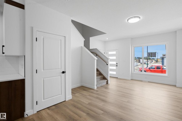 Open concept living area with light wood floors, white walls, and a view of the street through a large window. - 1547 211 St Nw, Edmonton