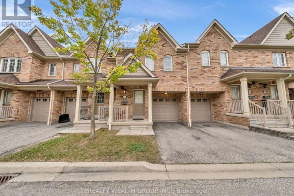 Front view of a brick townhouse complex with light brown siding and peaked roofs. - 155 - 5255 Palmetto Place, Mississauga