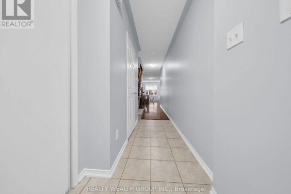 Interior hallway with light blue walls, beige tile floor, and view into living area. - 155 - 5255 Palmetto Place, Mississauga