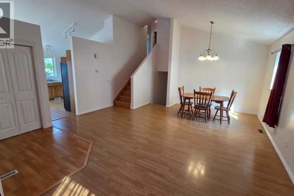 Open concept living and dining area with light wood floors, white walls, a staircase, and access to the kitchen. - 155 Applefield Close Se, Calgary