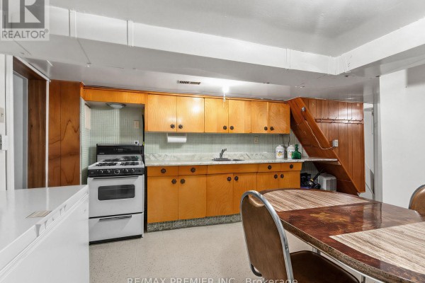 Kitchen with wooden cabinets, gas stove, and dining table - 155 Ascot Avenue Toronto