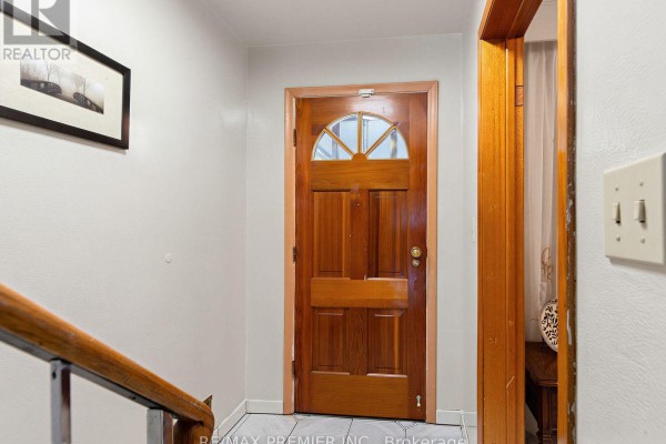 Interior view of a hallway with a wooden door and staircase railing. - 155 Ascot Avenue, Toronto
