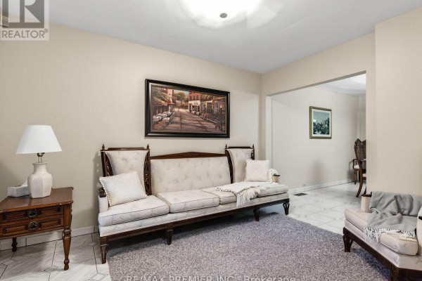 Living room with a long sofa, armchair, side table, and rug on tile floor. - 155 Ascot Avenue, Toronto