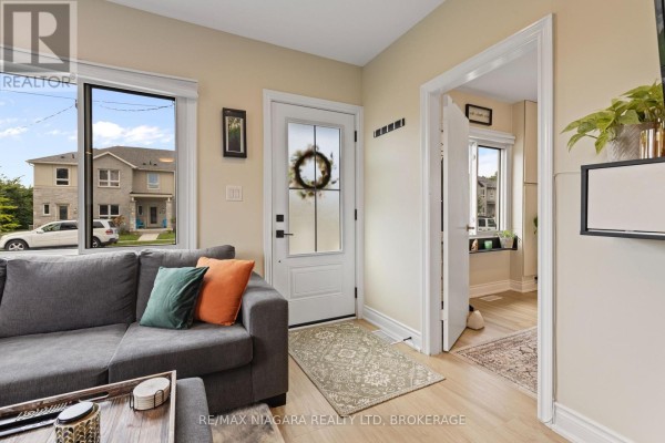 Living room with grey sectional, front door, and hallway view - 155 Broadway Street Welland