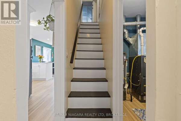 Staircase and furnace in hallway with kitchen view - 155 Broadway Street Welland