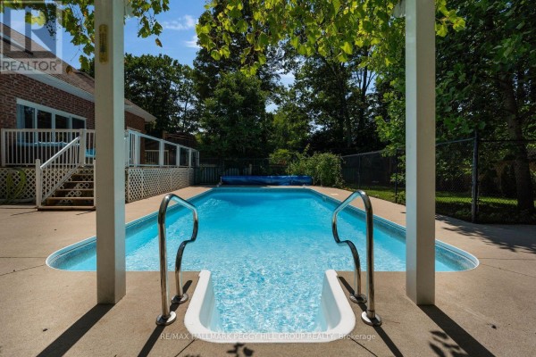 View of a backyard in-ground swimming pool with white steps and metal railings. - 155 Forest Glen Drive, Gravenhurst)