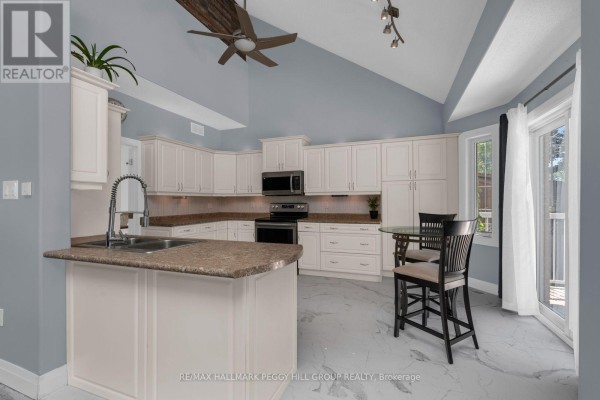 Modern kitchen with white cabinets, granite countertops, stainless steel appliances, and a small dining table. - 155 Forest Glen Drive, Gravenhurst)