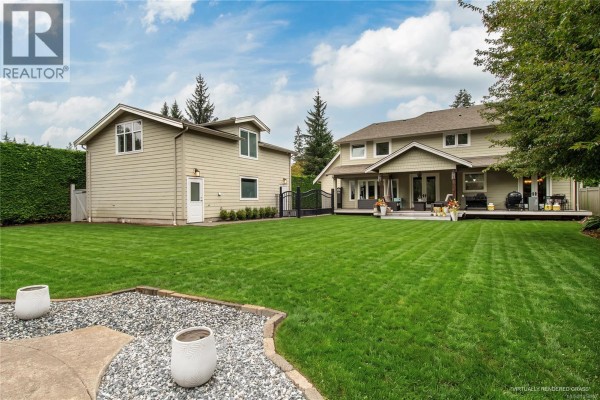 A covered patio with wicker furniture, a gas grill, and double glass doors. - 155 Redonda Way, Campbell River
