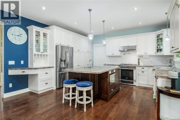 A spacious kitchen with white cabinetry, stainless steel appliances, and a large central island. - 155 Redonda Way, Campbell River