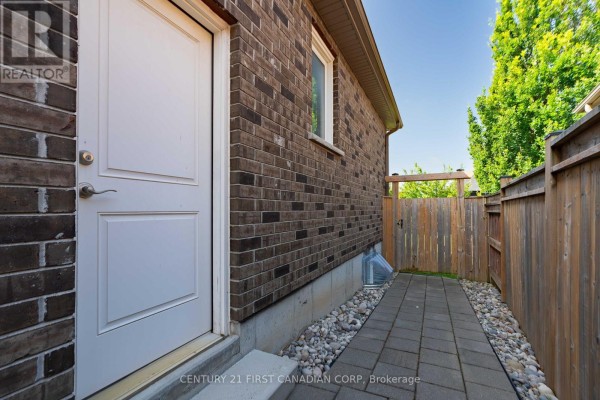 Side view of the house showing a brick wall, white door, and paved walkway. - 155 Spencer Avenue, Lucan Biddulph