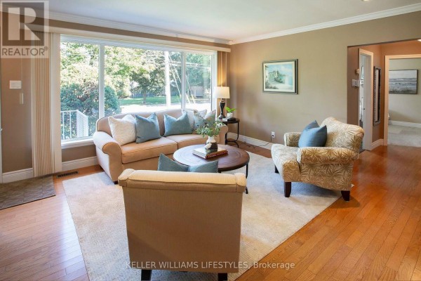 Living room with a beige sofa, armchairs, large picture window, and hardwood floors. - 155 Trowbridge Avenue, London South