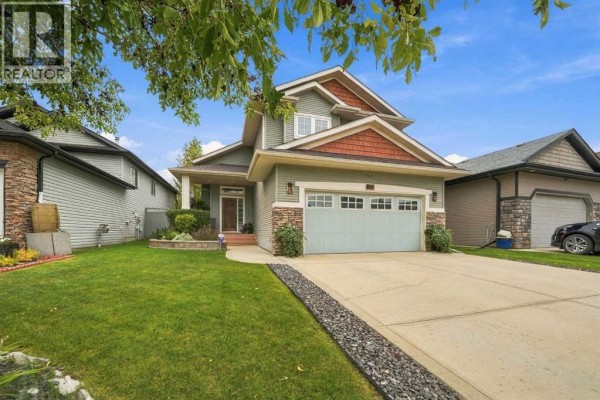Front view of a two-story house with a green exterior, stone accents, and a manicured lawn. - 155 Webster Drive, Red Deer