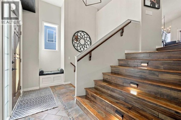 Interior view of a home entryway with a window bench, tiled floor, and a wood staircase. - 155 Webster Drive, Red Deer