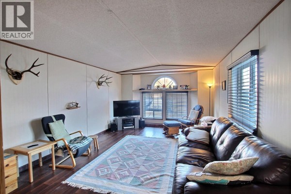 Living room with leather sofa, TV, and decorative antlers on walls - 1555 Howe Road Unit# 89, Kamloops