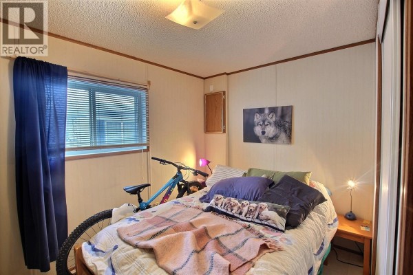 Cozy bedroom with a bike, bed, and artwork on the wall - 1555 Howe Road Unit# 89, Kamloops
