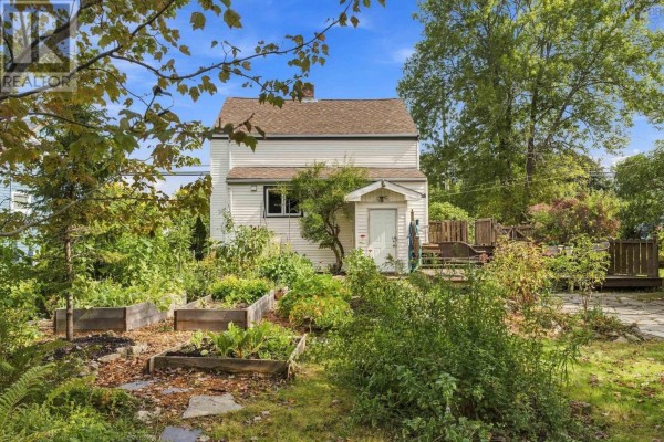 Rear exterior of the house with raised garden beds and dense surrounding foliage. - 1556 St Margarets Bay Road, Lakeside