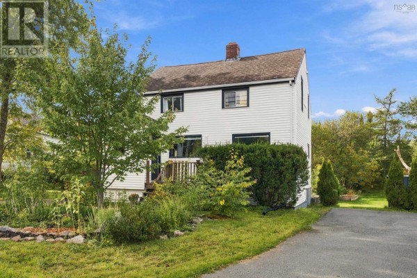 Side view of the house exterior with mature trees and a paved driveway. - 1556 St Margarets Bay Road, Lakeside