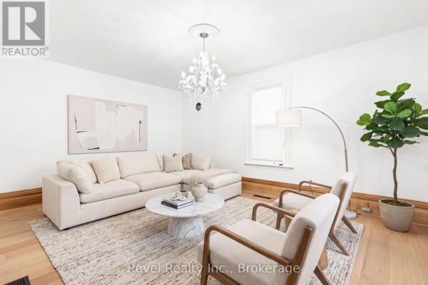 Living room with white walls, a sectional sofa, two armchairs, a marble coffee table, and a chandelier. - 15578 Simcoe Street, Scugog