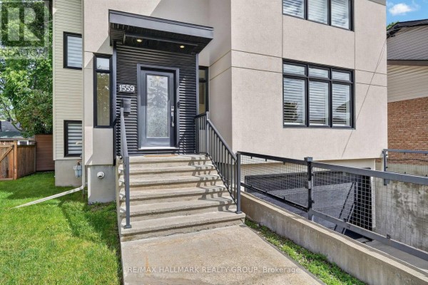 Close-up of the front entrance with concrete steps, black railing, and modern door. - 1559 Queensdale Avenue, Ottawa