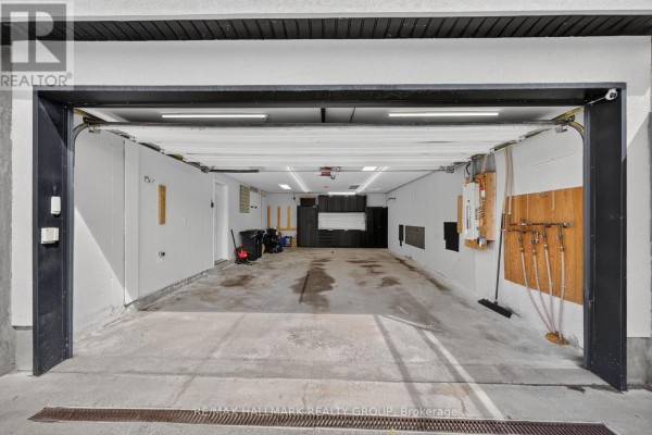 Spacious, empty two-car garage with concrete floor and overhead lighting. - 1559 Queensdale Avenue, Ottawa