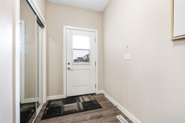 Interior foyer with a white door, mirrored closet, and dark wood laminate flooring. - 156 1655 Leila Avenue, Winnipeg