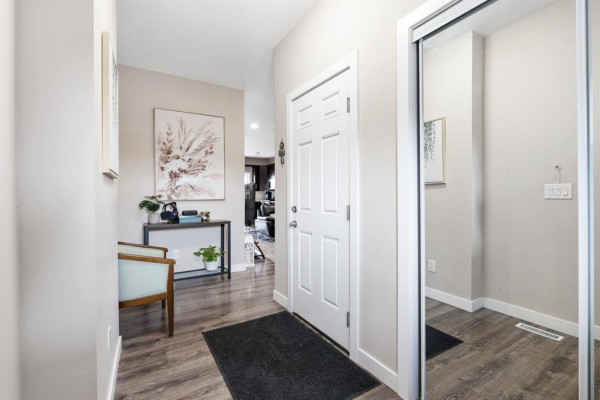 Foyer with a white door, mirrored closet, and a console table with decor. - 156 1655 Leila Avenue, Winnipeg