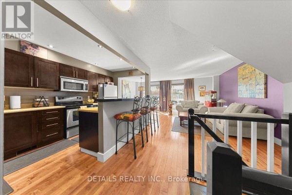 Kitchen with dark wood cabinets and island, adjacent to living room. - 156 Birch Hill Private N, Ottawa