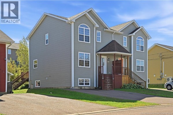 Side exterior of a grey townhouse showing multiple windows and dark grey vinyl siding. - 156 Houlahan Street, Dieppe