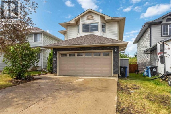 Front exterior of a two-story house with a beige garage door and light siding. - 156 J.w. Mann Drive, Fort Mcmurray