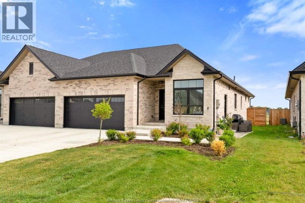 Exterior side view of a brick townhouse with a double garage and green lawn. - 156 Mclellan Avenue Unit# B (lower), Amherstburg