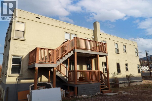 Back deck and stairs with wooden railings and supports attached to the building. - 156 Nanaimo Avenue E, Penticton
