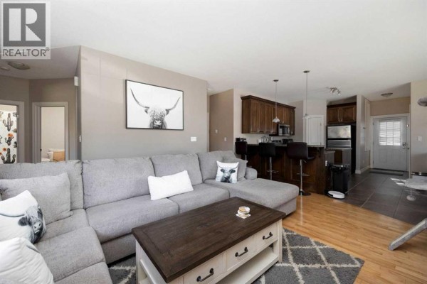 Living room with a large sectional sofa, coffee table, and view of the kitchen. - 156 Paris Crescent, Fort Mcmurray