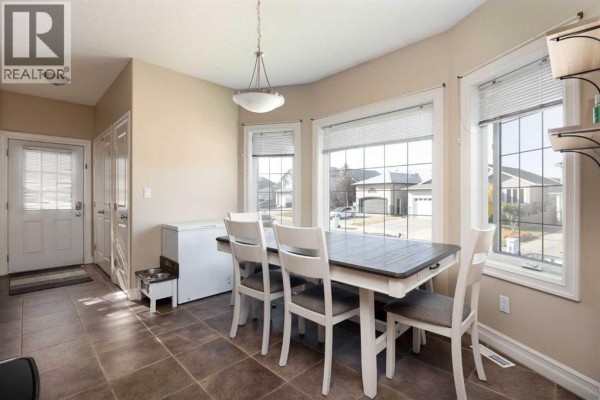 Dining area with a table and chairs near a chest freezer and a doorway. - 156 Paris Crescent, Fort Mcmurray