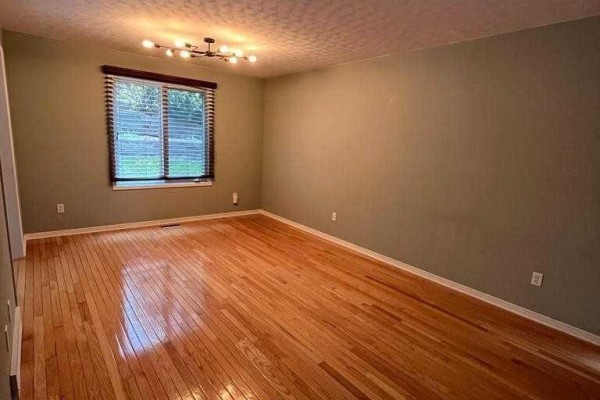 Spacious room with hardwood floors, large window, and a contemporary chandelier. - 156 Pochard Lane, London East