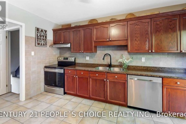Kitchen with light brown tile floors, dark wood cabinets, stainless steel appliances, and a double sink. - 156 Pochard Lane, London East