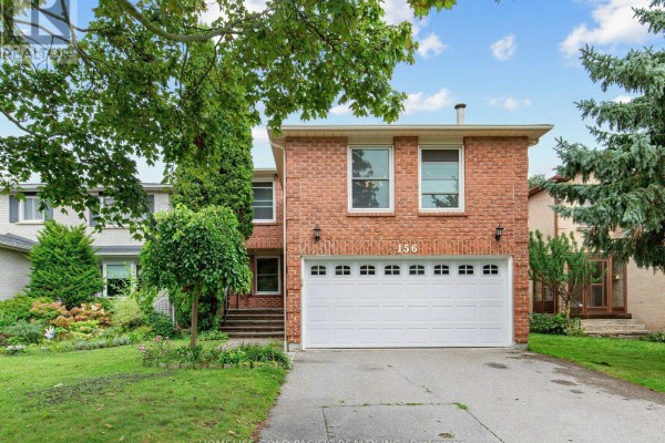 Red brick house with white garage door, green trees, and a paved driveway. - 156 Ravenscroft Road, Ajax