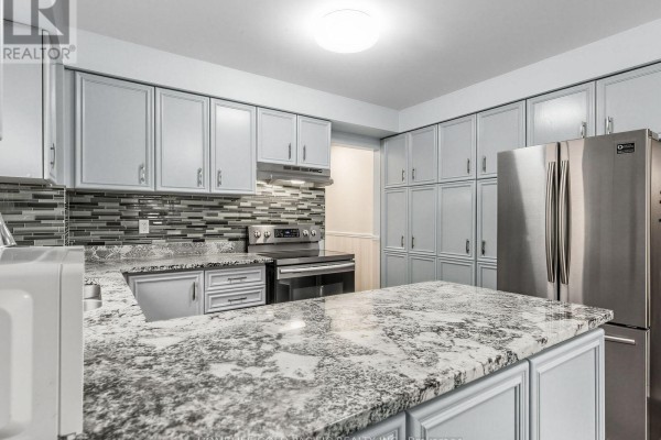 Renovated kitchen with granite island, stainless steel appliances, and grey cabinets - 156 Ravenscroft Road Ajax